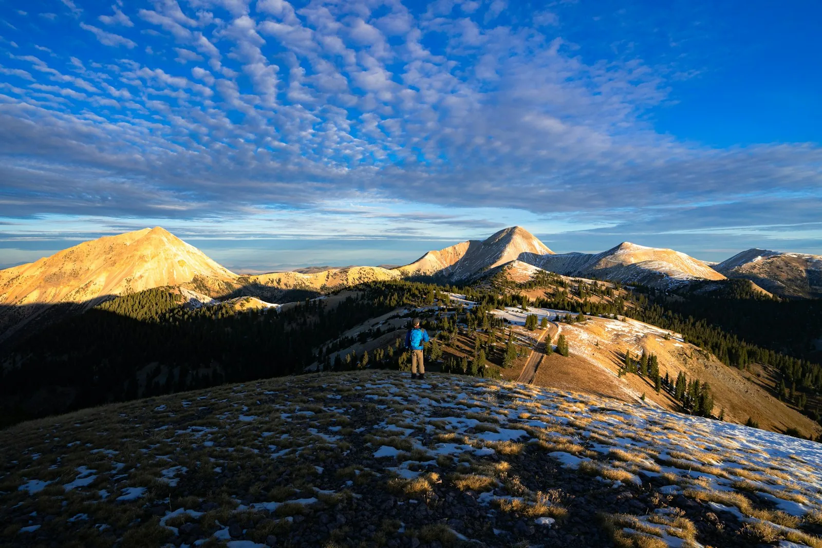 A hiker standing above a mountain valley at sunrise